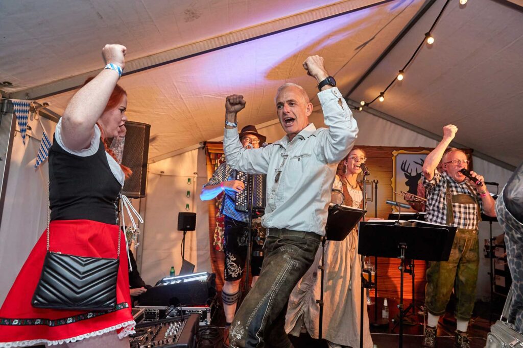 Publikum danser entusiastisk foran scenen, mens bandet spiller energisk musik.